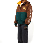 Side view of a Male Model wearing a brown and forest green jacket with yellow accents on a white background