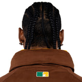 Close up Rear view of a Male Model wearing a brown with the 'NY Tough' logo embroidered on the neck. 