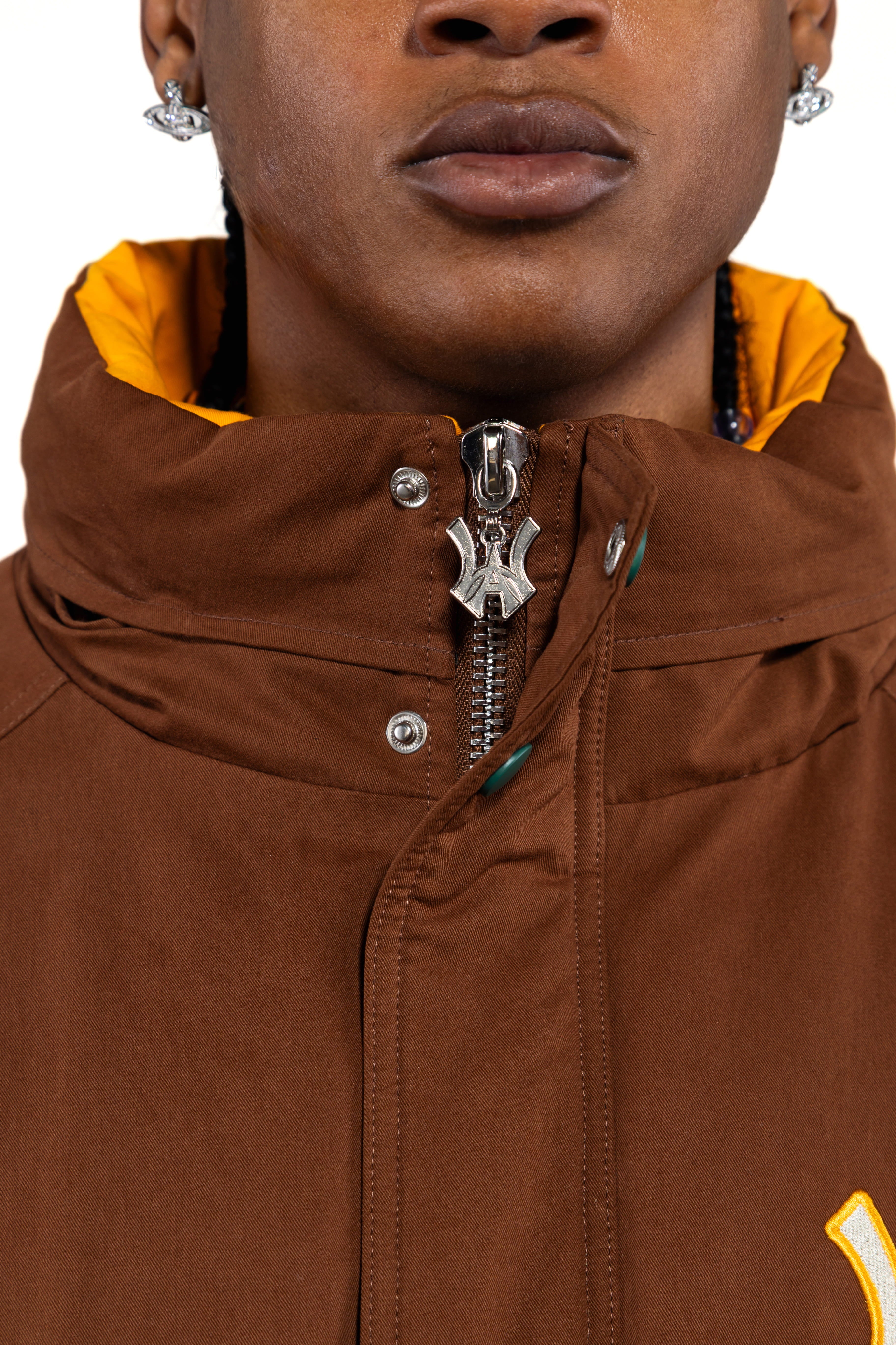 Close-up of a brown jacket with a 'WA' logo zipper.