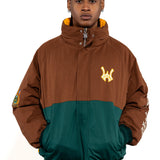 Close up view of a Male Model wearing a brown and forest green jacket with yellow accents on a white background. 'WA' Logo embroidered on the left 