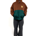 Male Model wearing a brown and green jacket with a embroidered 'WA' logo on a white background