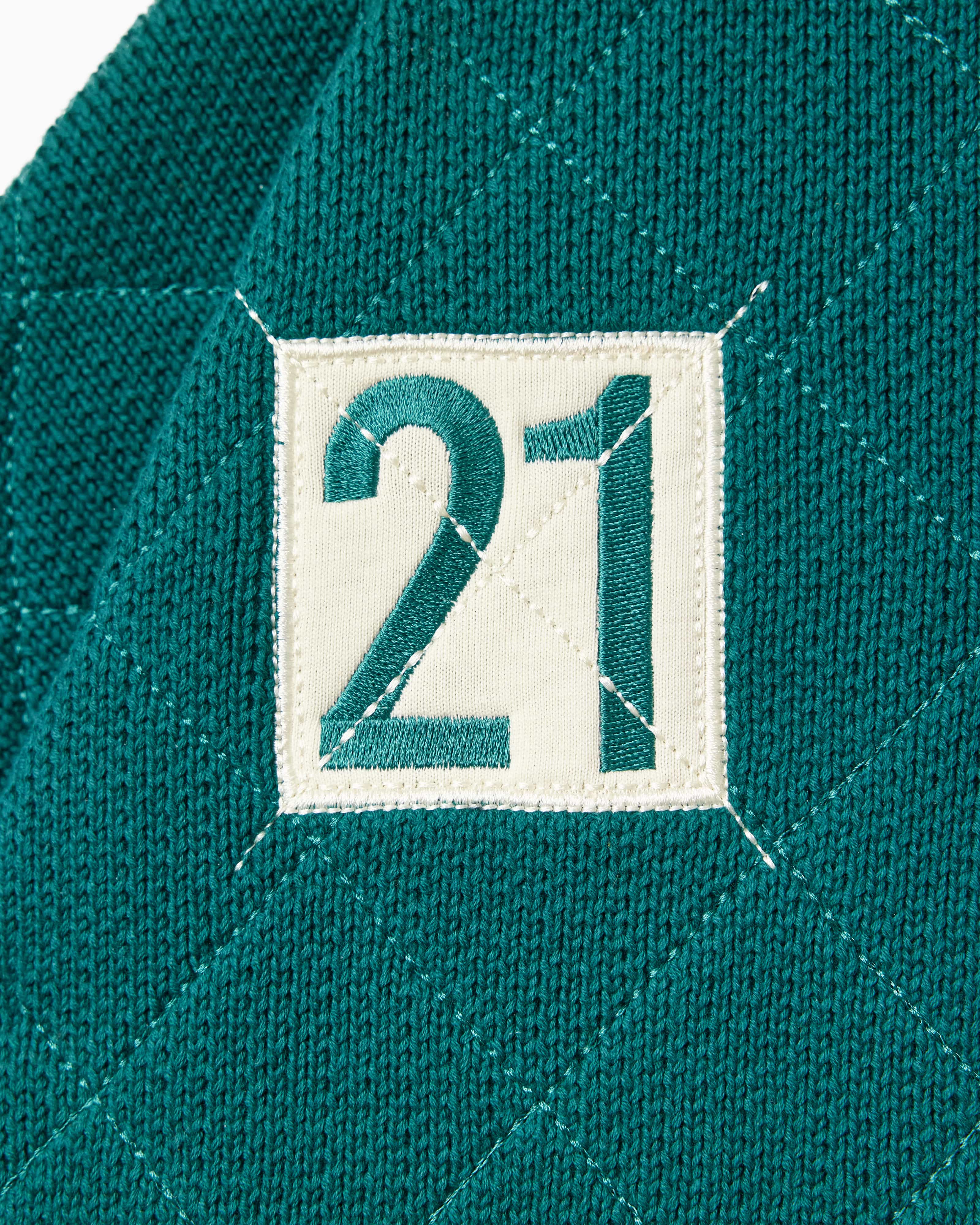 Close up of the number 21 within a cream box on the right chest of the WOA knit rugby polo.