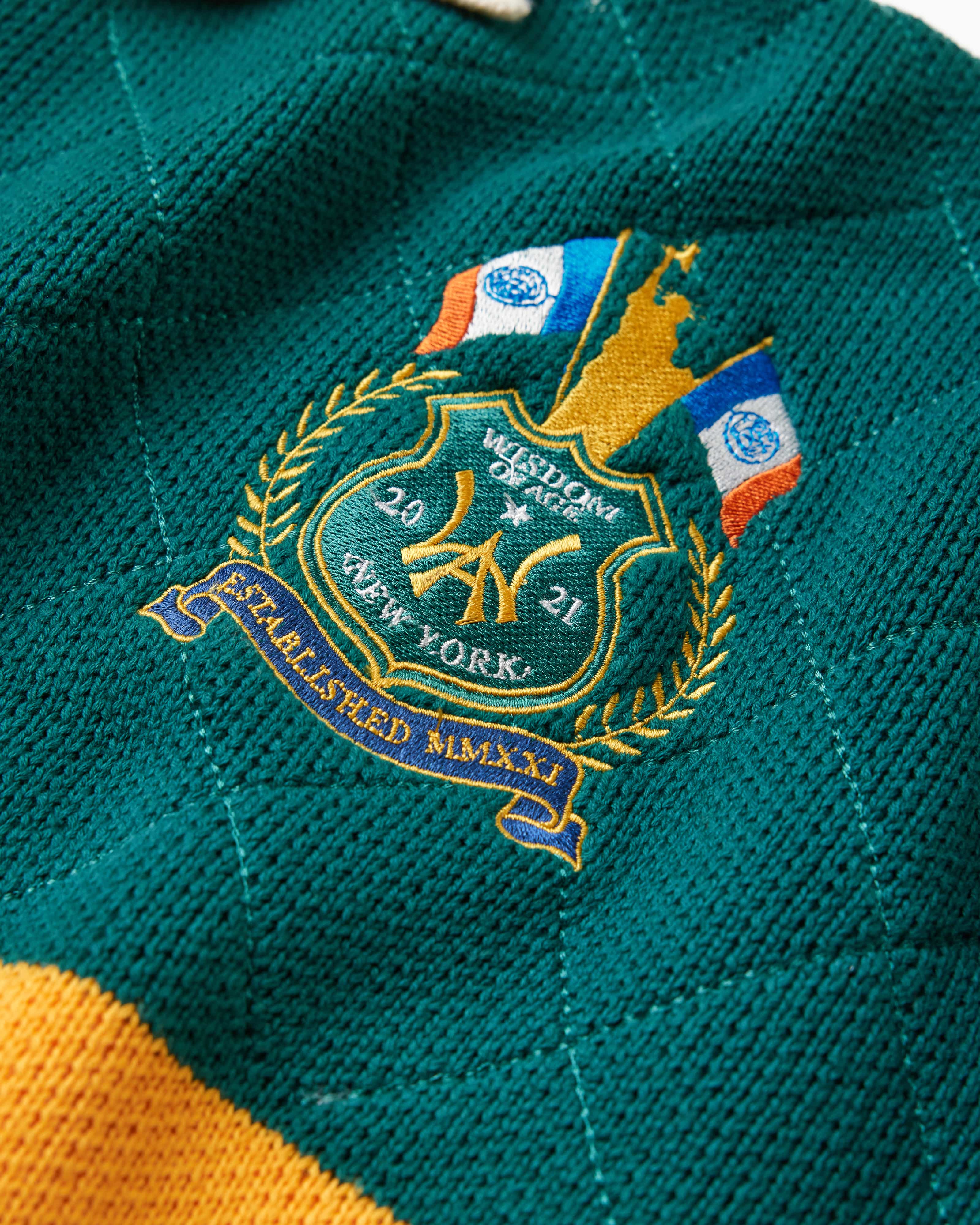 Close up of the embroidered Wisdom of age NY state patch on the left shoulder. The patch features a silhoutte of the Statue Of Liberty holding a firearm, 2 New York state flags, the WA logo the number 20 on the left, the number 21 on the right in gold thread.