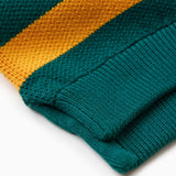 Close up of the bottom of the WOA knit rugby polo. Green polo with a yellow stripe.