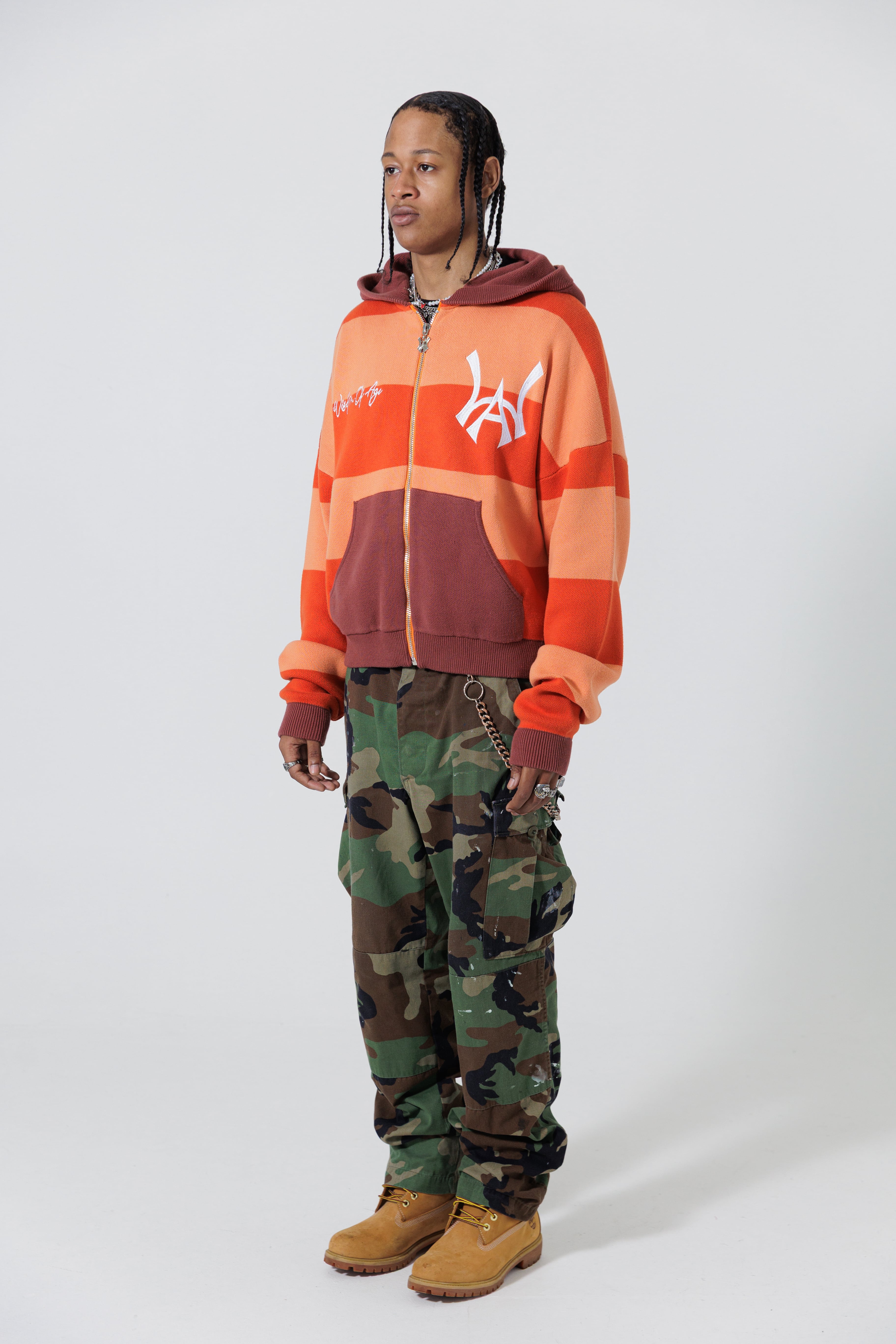 Front Full Body View Of A Male Model wearing The Wisdom Of Age Knit Hoodie Orange.