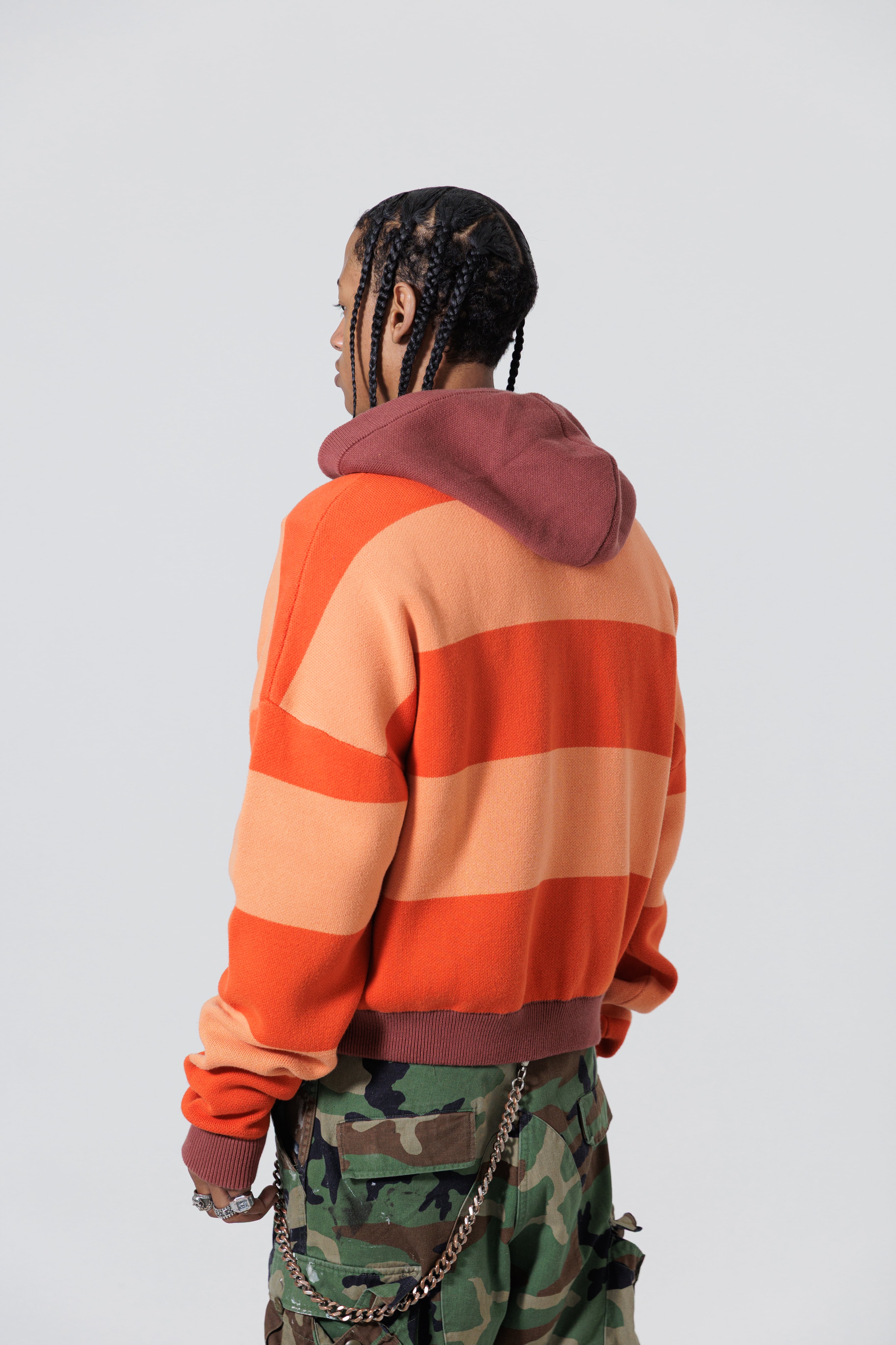 Rear Side View Of A Male Model wearing The Wisdom Of Age Knit Hoodie Orange.