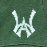 Close-up of a sage green fabric with a white WA logo on a textured background