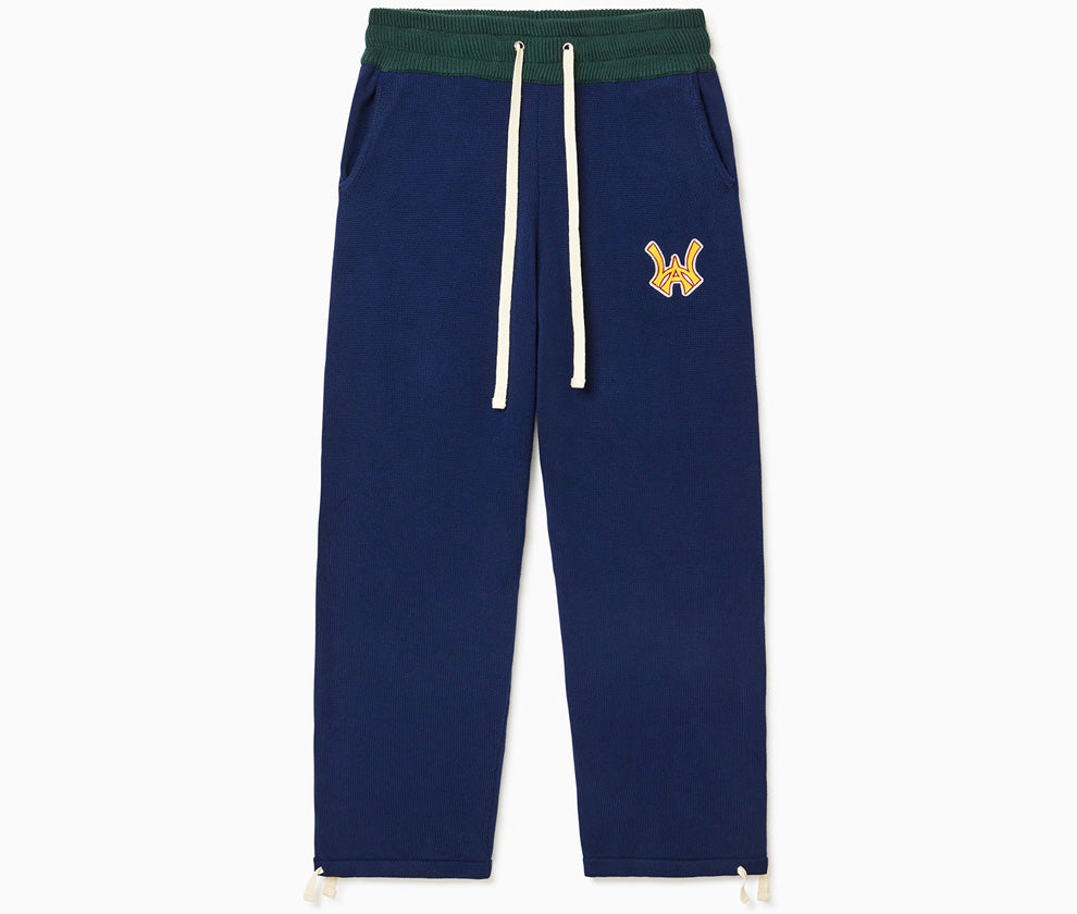 The Wisdom Of Age Knit Clinton Sweatpants Navy Front View. Embroidered Yellow WA logo with a white outline on the left mid-hip. Off-White drawstrings on a dark green waistband