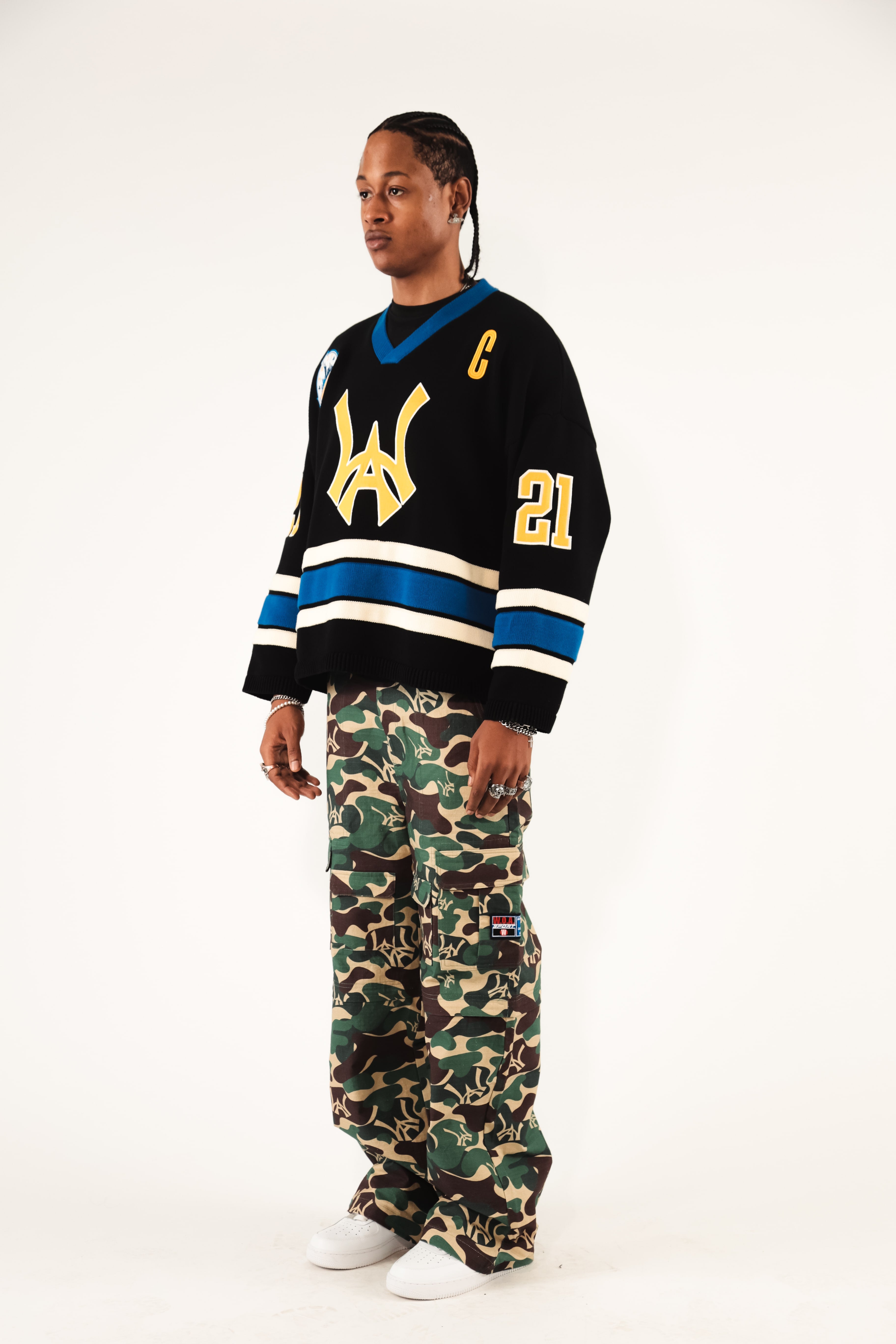 Side view Male Model wearing WOA Hockey Jersey - Static Shock with a yellow WA logo and camouflage pants on a white background