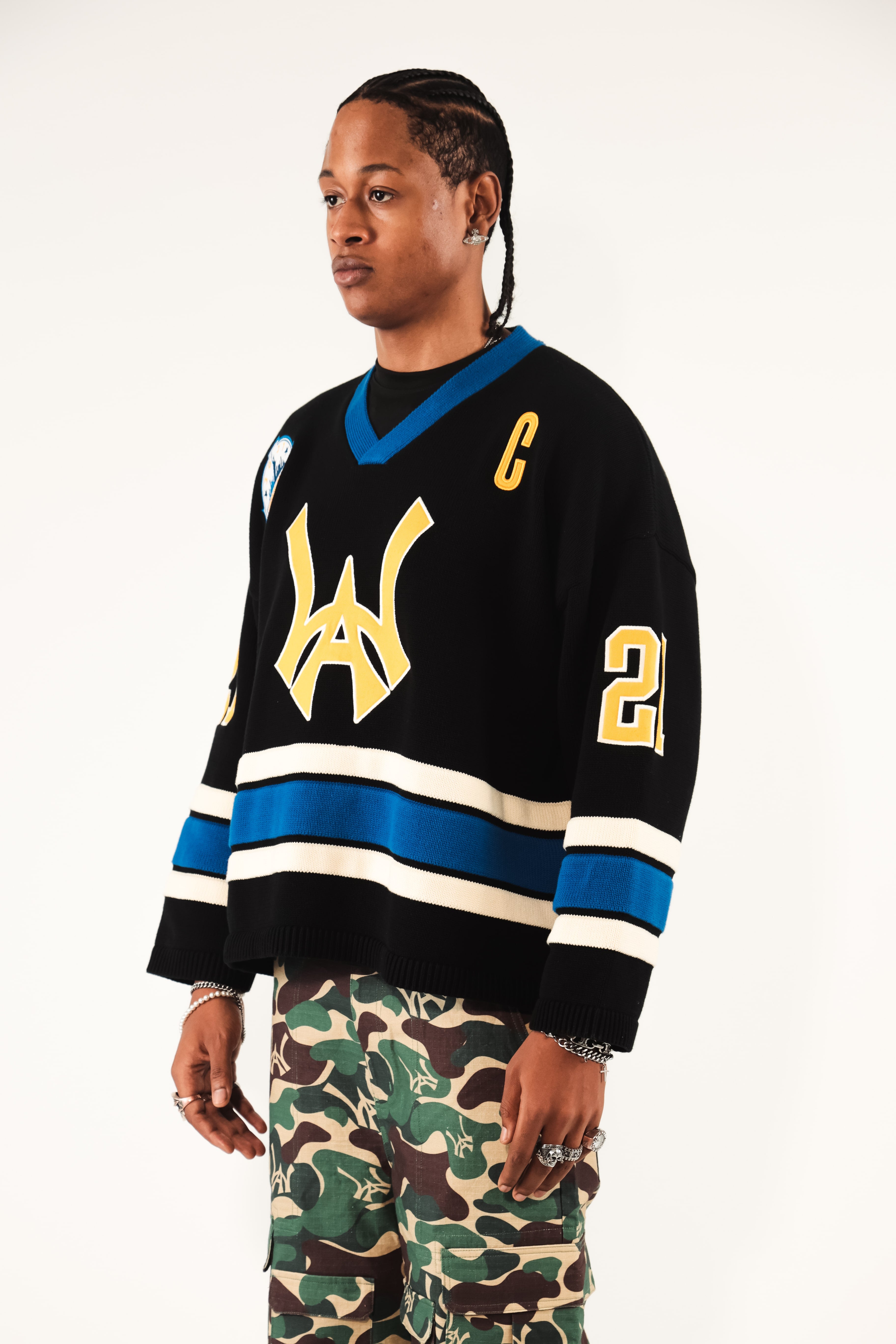 Male Model wearing WOA Hockey Jersey - Static Shock with a yellow WA logo and camouflage pants on a white background