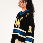 Female model Wearing The Knitted Wisdom Of Age Hockey Jersey - Static Shock with yellow and blue details on a white background