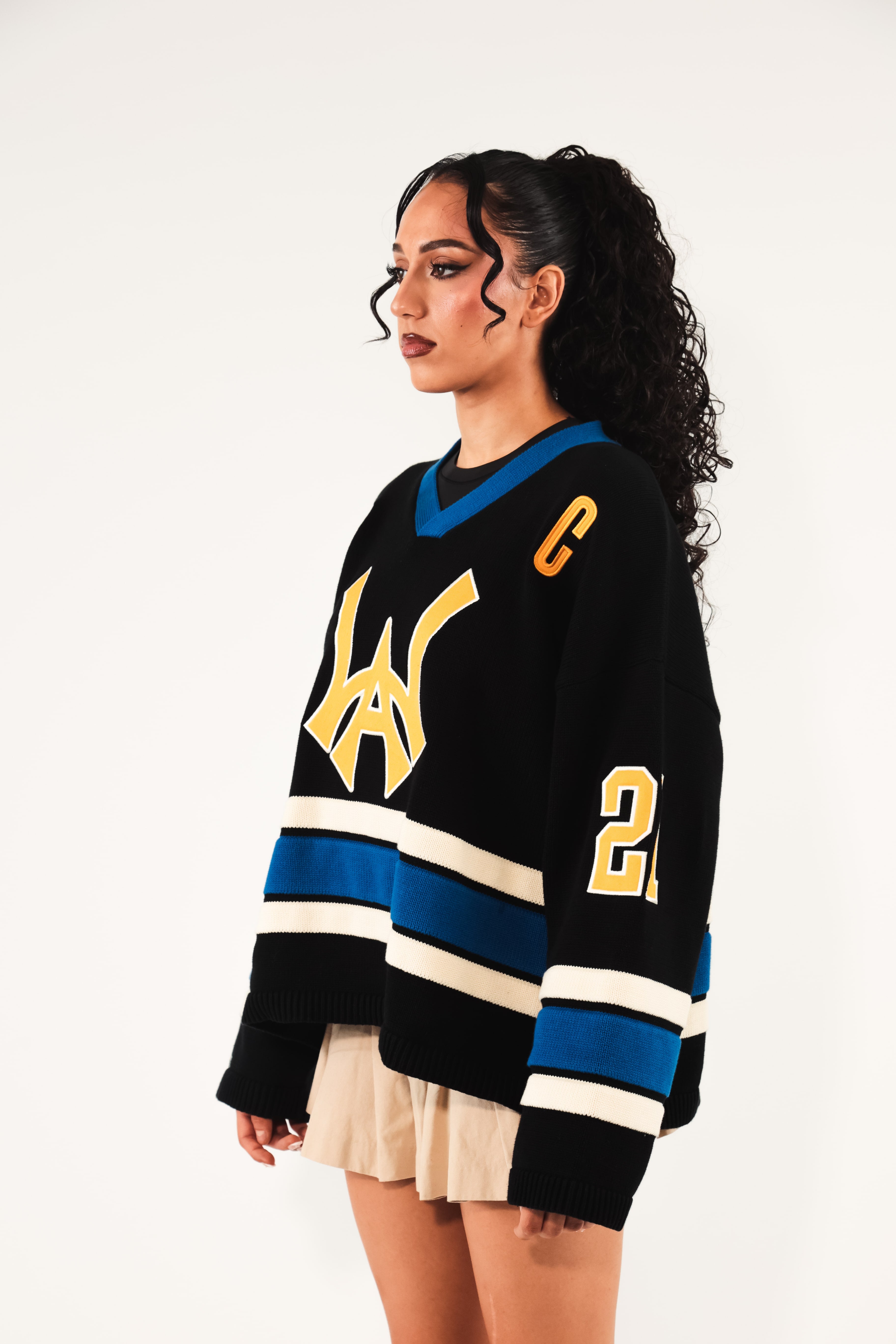 Female model Wearing The Knitted Wisdom Of Age Hockey Jersey - Static Shock with yellow and blue details on a white background