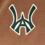 Close-up of a green WA logo with white outline on a brown textured background