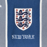 Close-up of a knitted soccer jersey with a crest and 'New York' text on a blue and gray striped background.