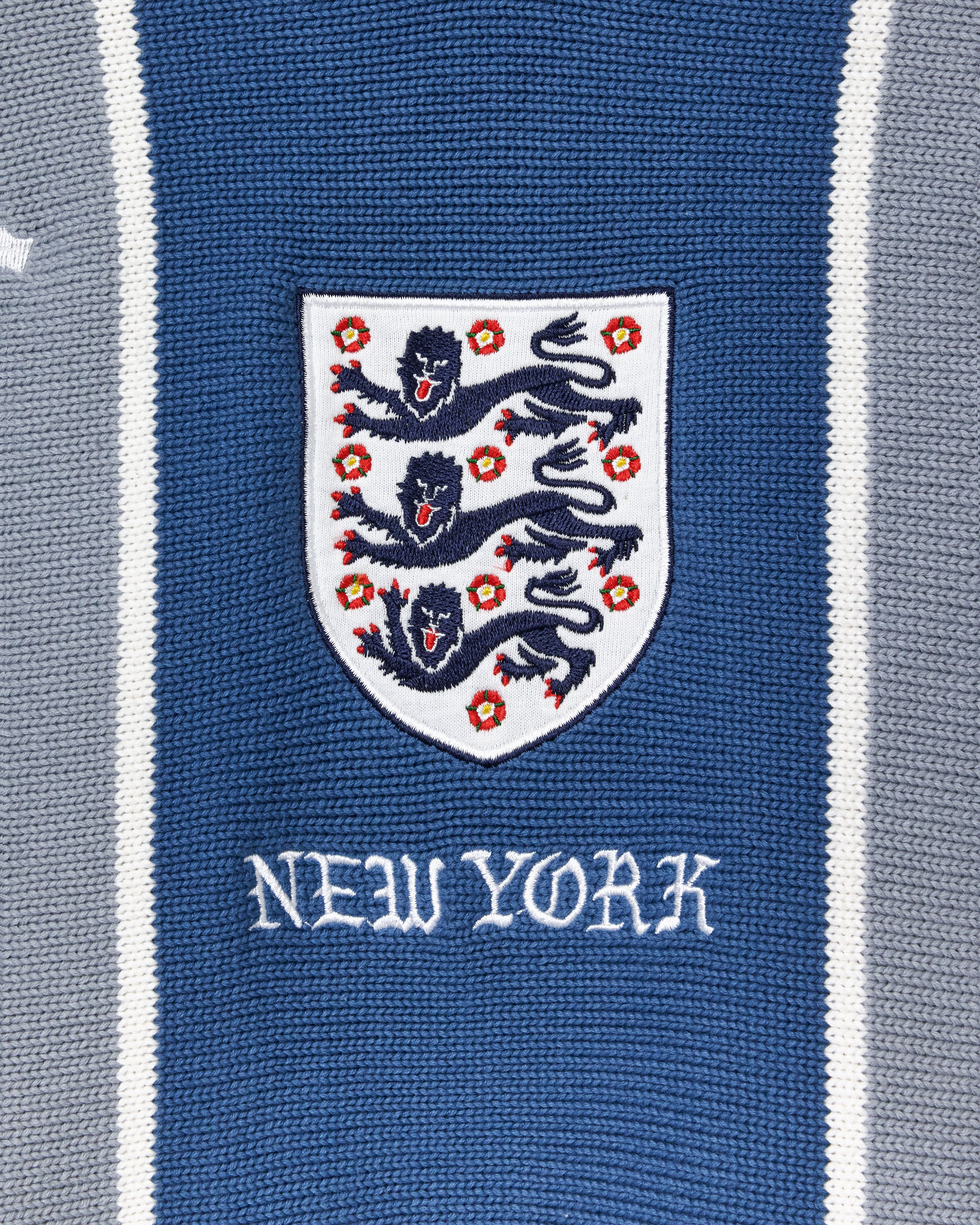 Close-up of a knitted soccer jersey with a crest and 'New York' text on a blue and gray striped background.