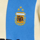 Close-up of a knitted soccer jersey with the Argentina national crest on a blue and beige jersey.