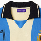 Close-up of a blue and beige knitted soccer jersey with the Wisdom Of Age label on a white background