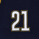 Close-up of a black knitted soccer jersey with the number 21 embroidered in white and gold.
