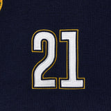 Close-up of a black knitted soccer jersey with the number 21 embroidered in white and gold.