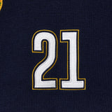 Wisdom Of Age Knit Soccer Jersey RIo. Close-up of a black knitted soccer jersey with the number 21 embroidered in white and gold.