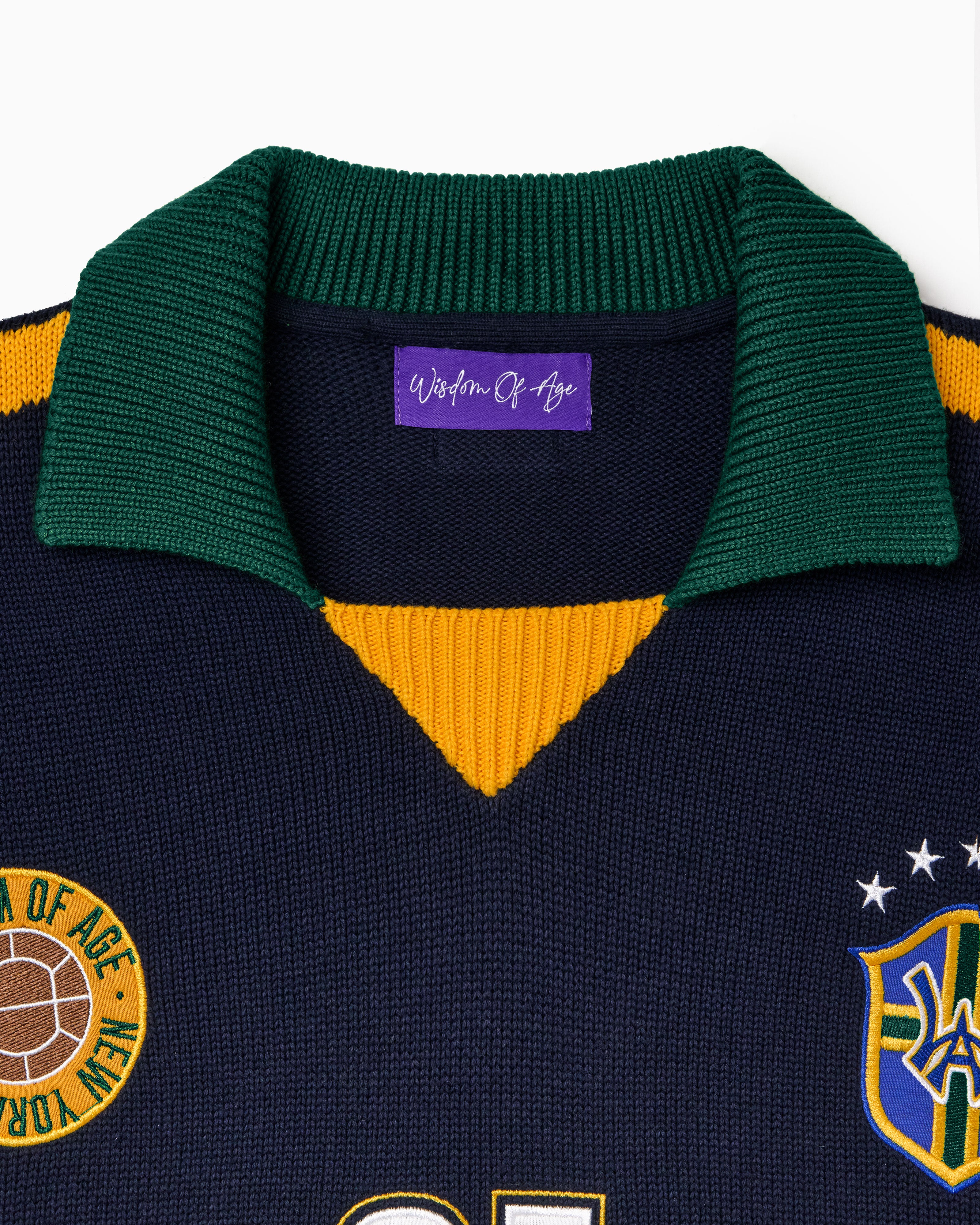 Wisdom Of Age Knit soccer jersey Rio. Black Knitted Soccer Jersey with green collar, yellow accents, and logos on a white background