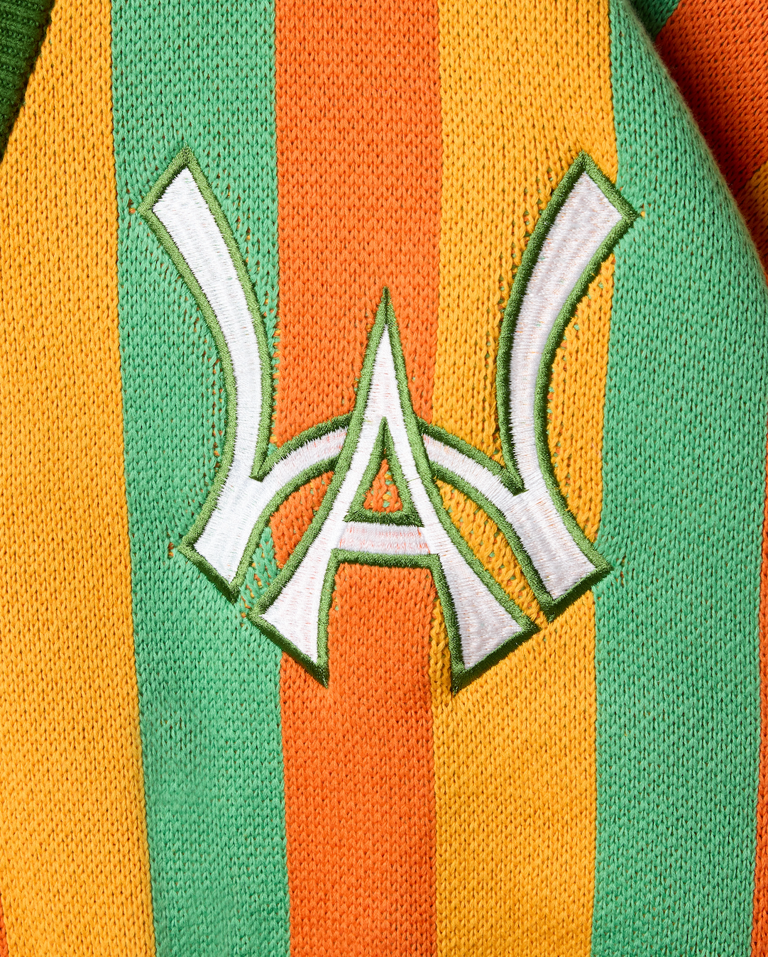 Closer look at the brand logo in a monogram font of connecting the "W" and "A" located on the upper left chest of the cardigan.