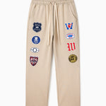 Wisdom Of Age Sandstone sweatpants with various Patches on a white background
