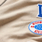 Close-up of the wisdom of age sand stone sweat pants fabric with patches.