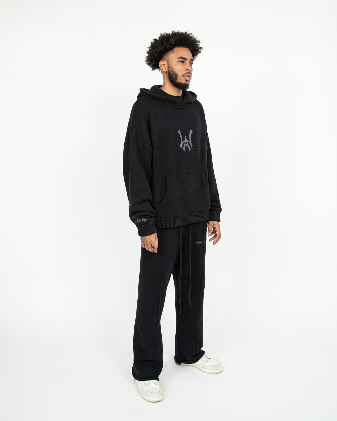 Head to toe angled side profile of the WOA Knit Hoodie in Black.The Knit Hoodie is paired with the Knit Sweatpants in black.